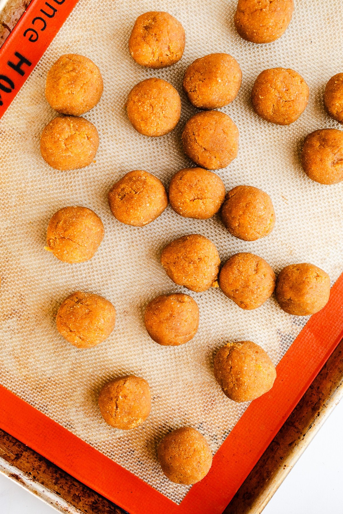 Raw pumpkin balls on a baking sheet.