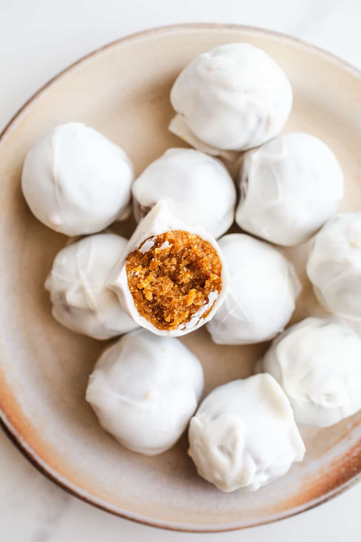 White chocolate pumpkin balls on a plate.