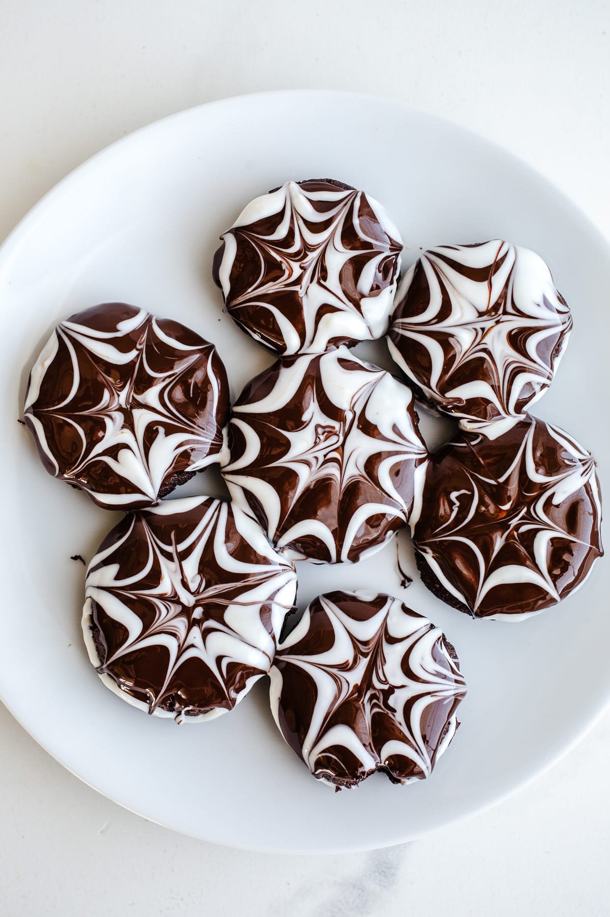 Chocolate spiderweb cookies on a plate. 