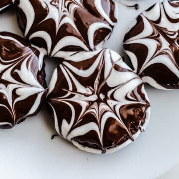 Chocolate cookies with a spiderweb glaze on a plate.