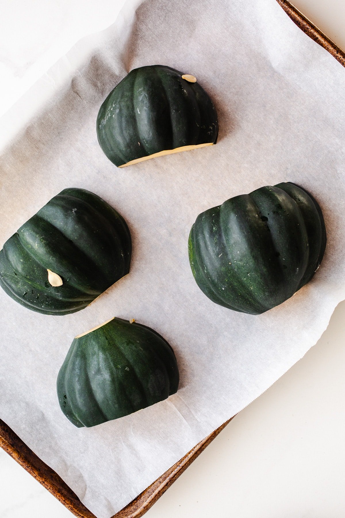 Acorn squash halves on a baking sheet. 