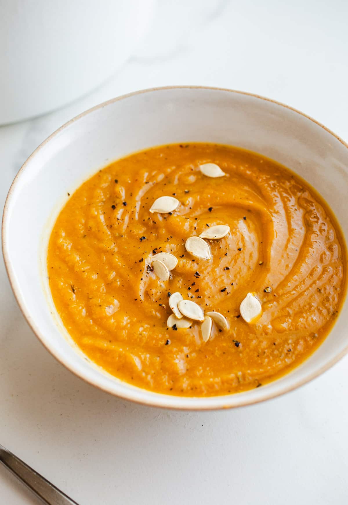 Squash soup in a bowl topped with acorn seeds.