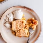 A piece of apple dump cake on a plate with ice cream.