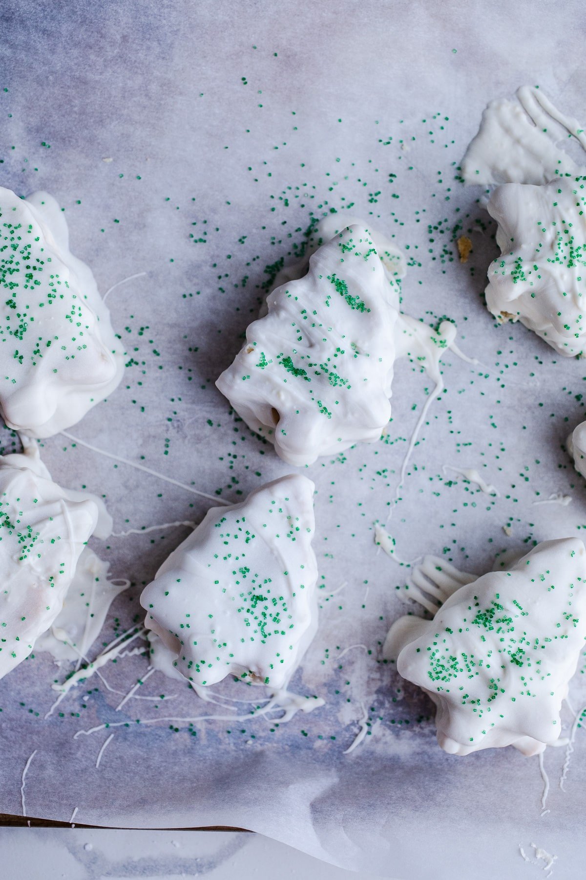 Christmas tree cakes dipped in white chocolate with green sprinkles.
