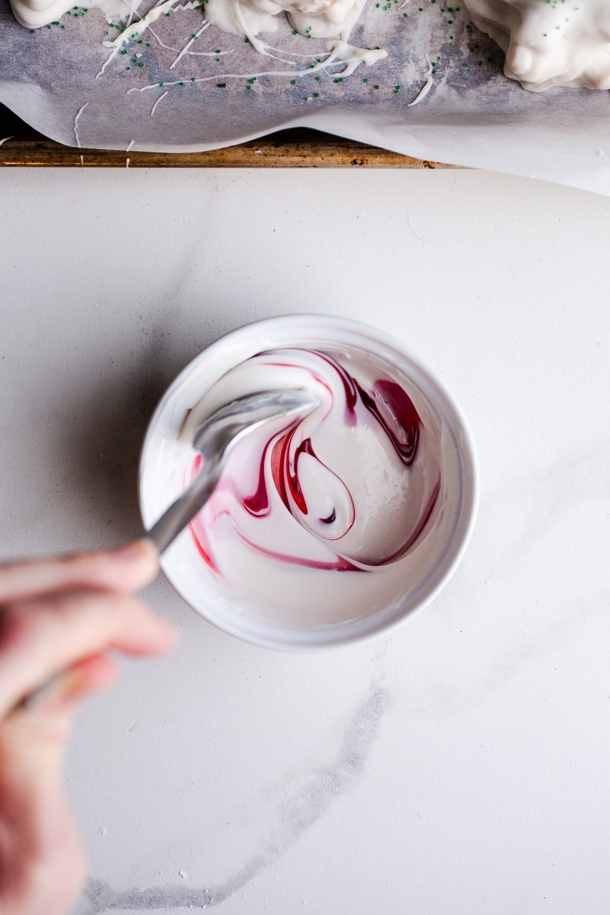 Melted white chocolate in a bowl with food coloring.
