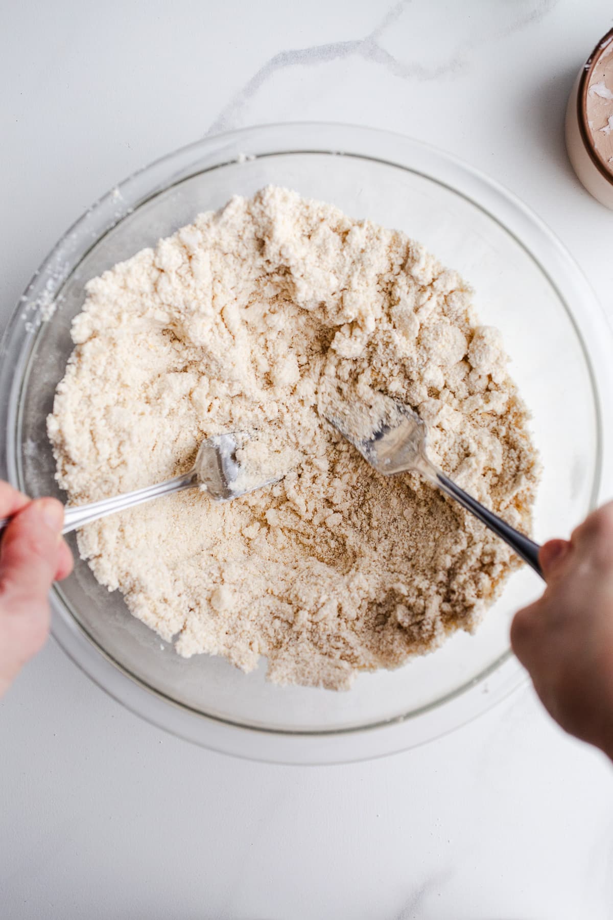 Coconut oil being mixed into flour in a mixing bowl.