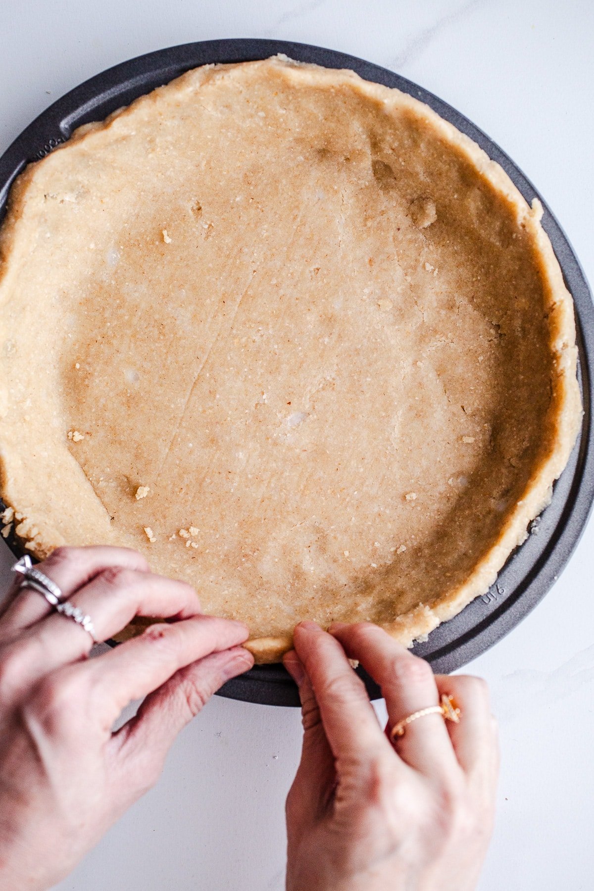 Crimping pie crust in a pan.