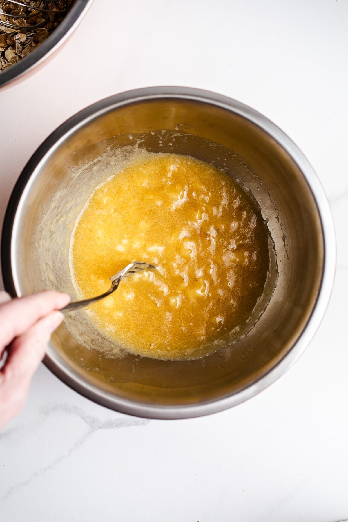 Mashed banana and maple syrup in a mixing bowl.