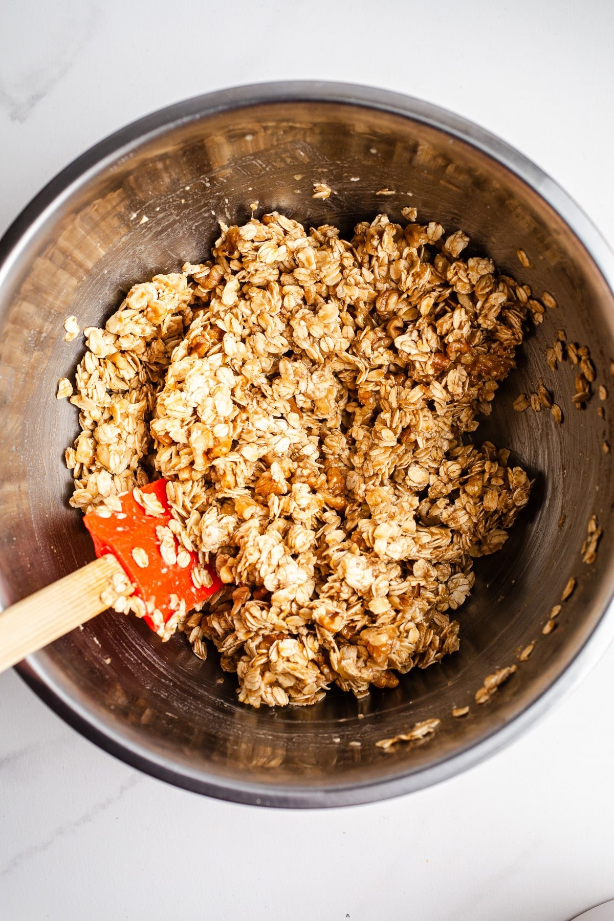 Coated oats and walnuts in a mixing bowl. 