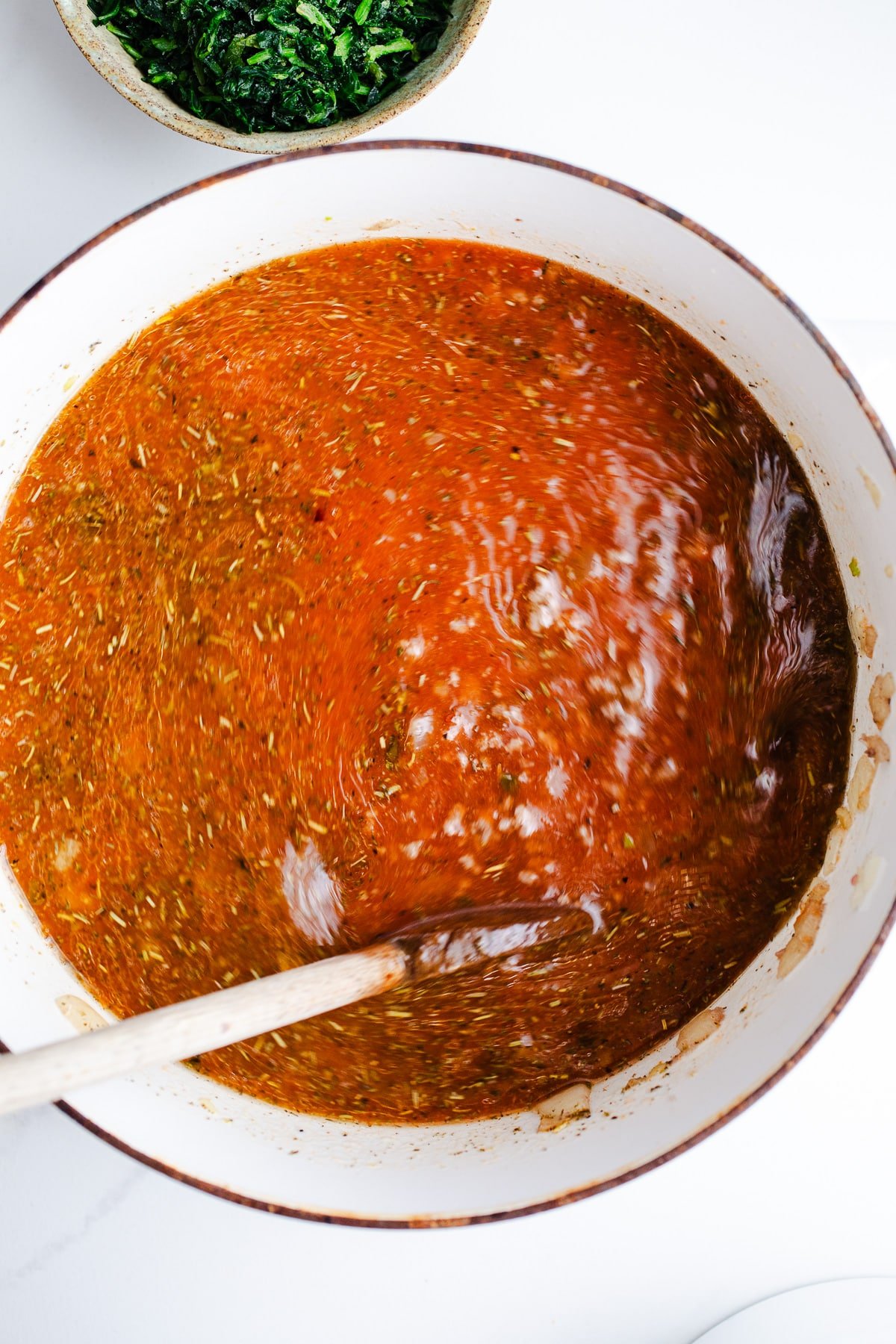 Marinara and broth in a white pot. 