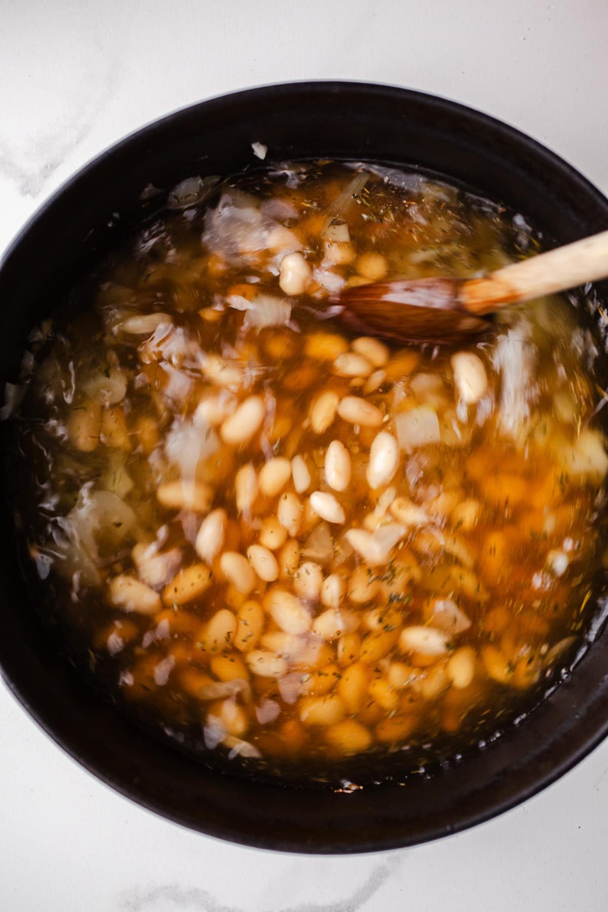 White beans in broth in a large pot.