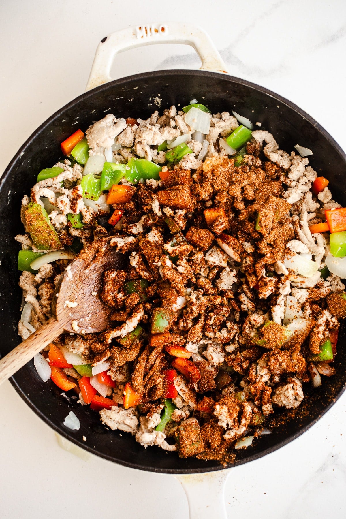 Seasoning on top of turkey and peppers in a skillet.