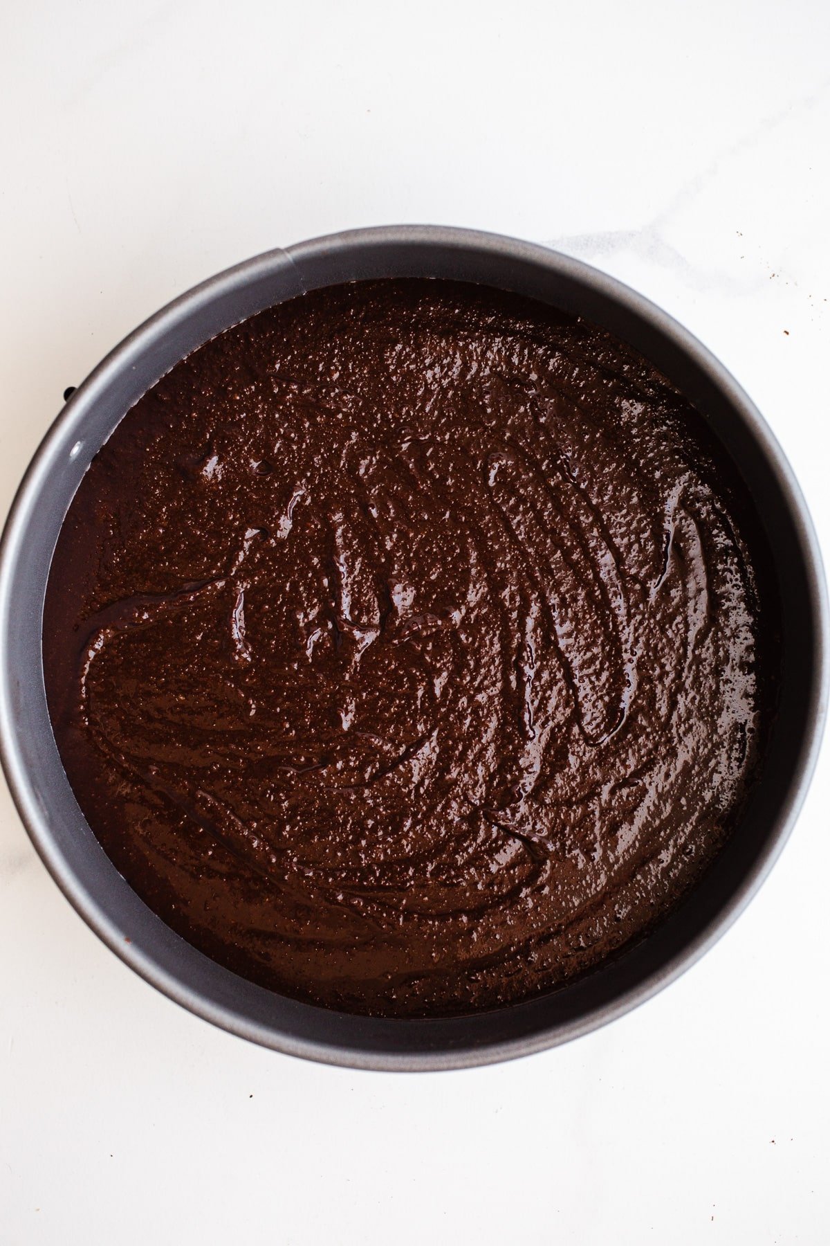 Chocolate cake batter in a round cake pan.