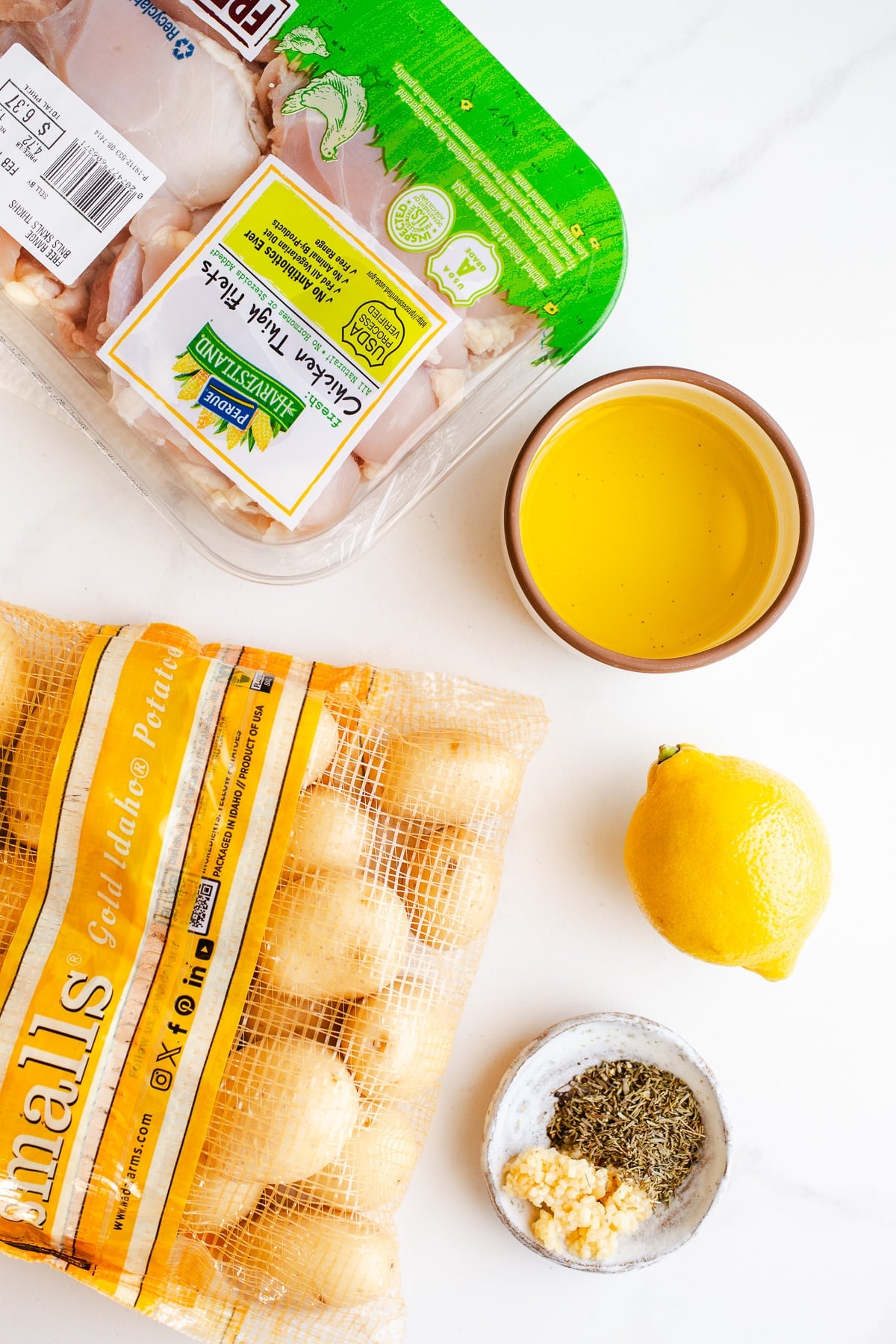 Ingredients to make lemon garlic chicken on a marble surface.