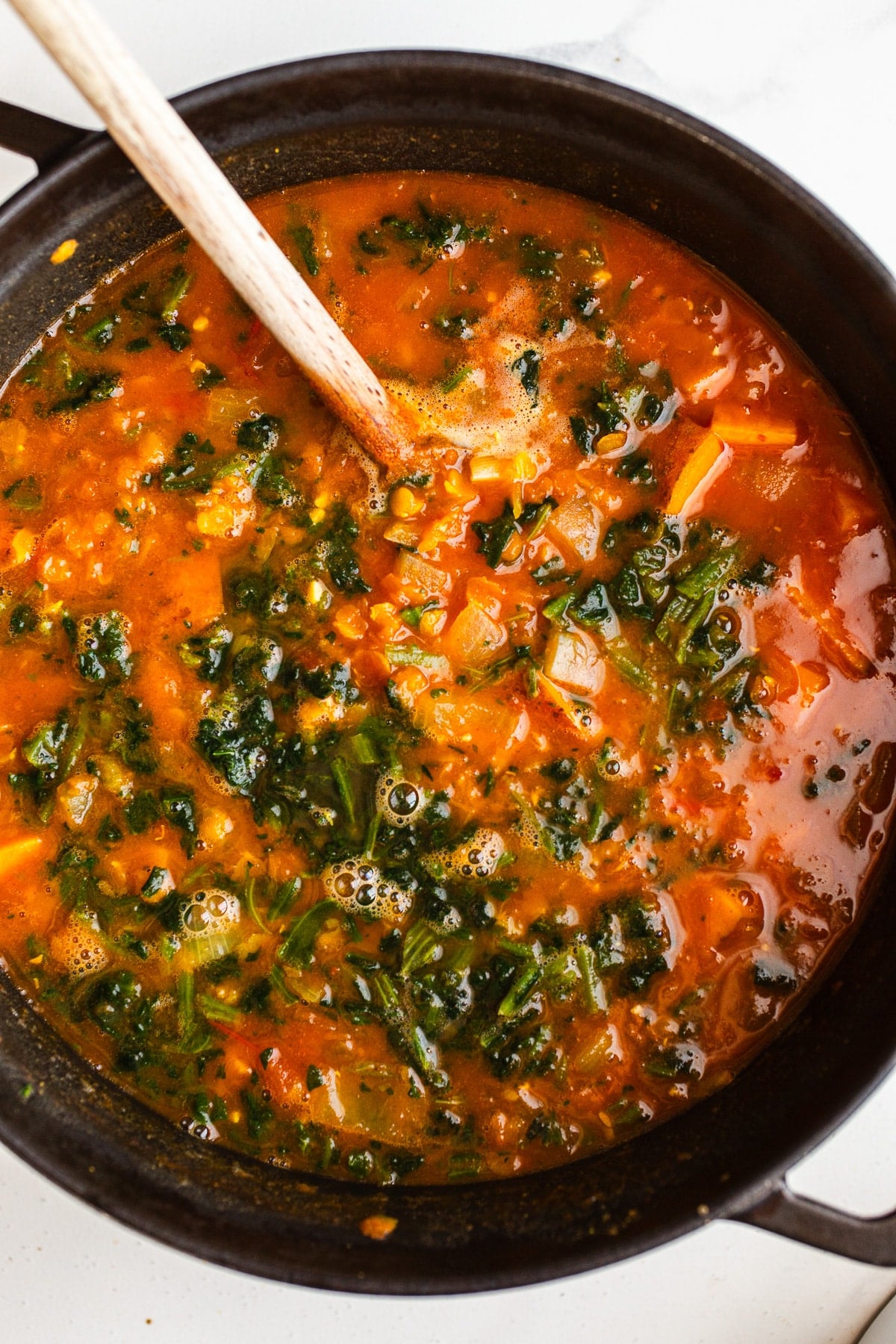 Spinach stirred into a pot of soup.