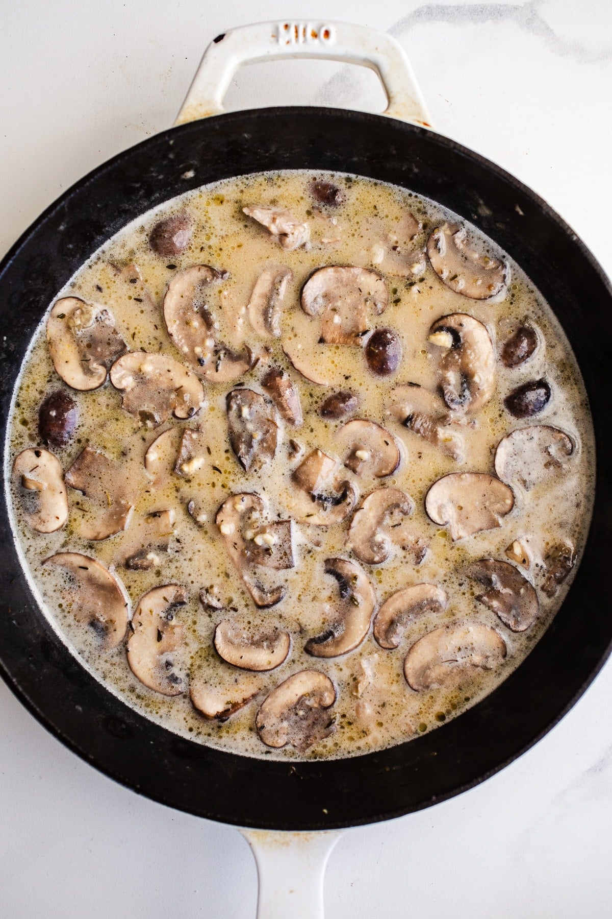 Coconut milk, broth, and mushrooms in a skillet.