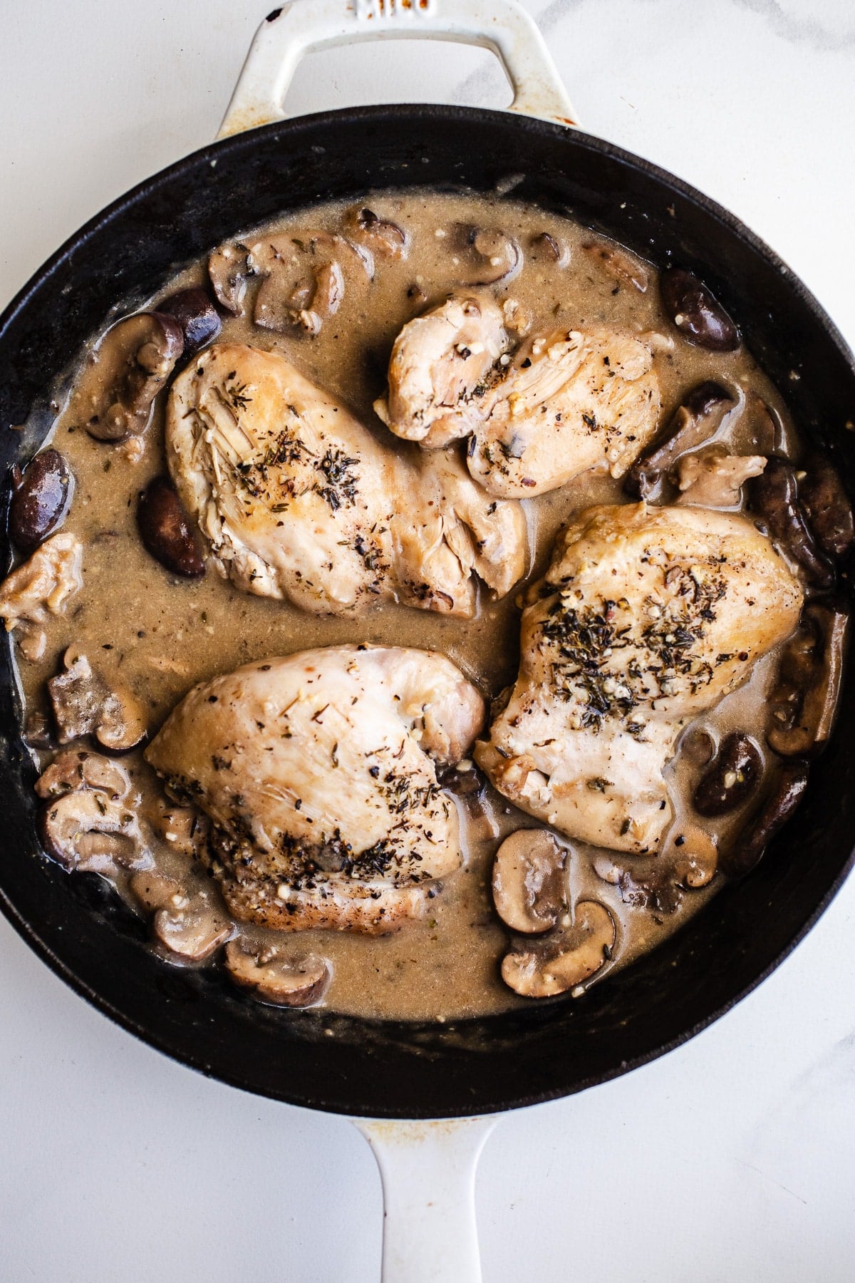 Chicken and mushrooms in a skillet.