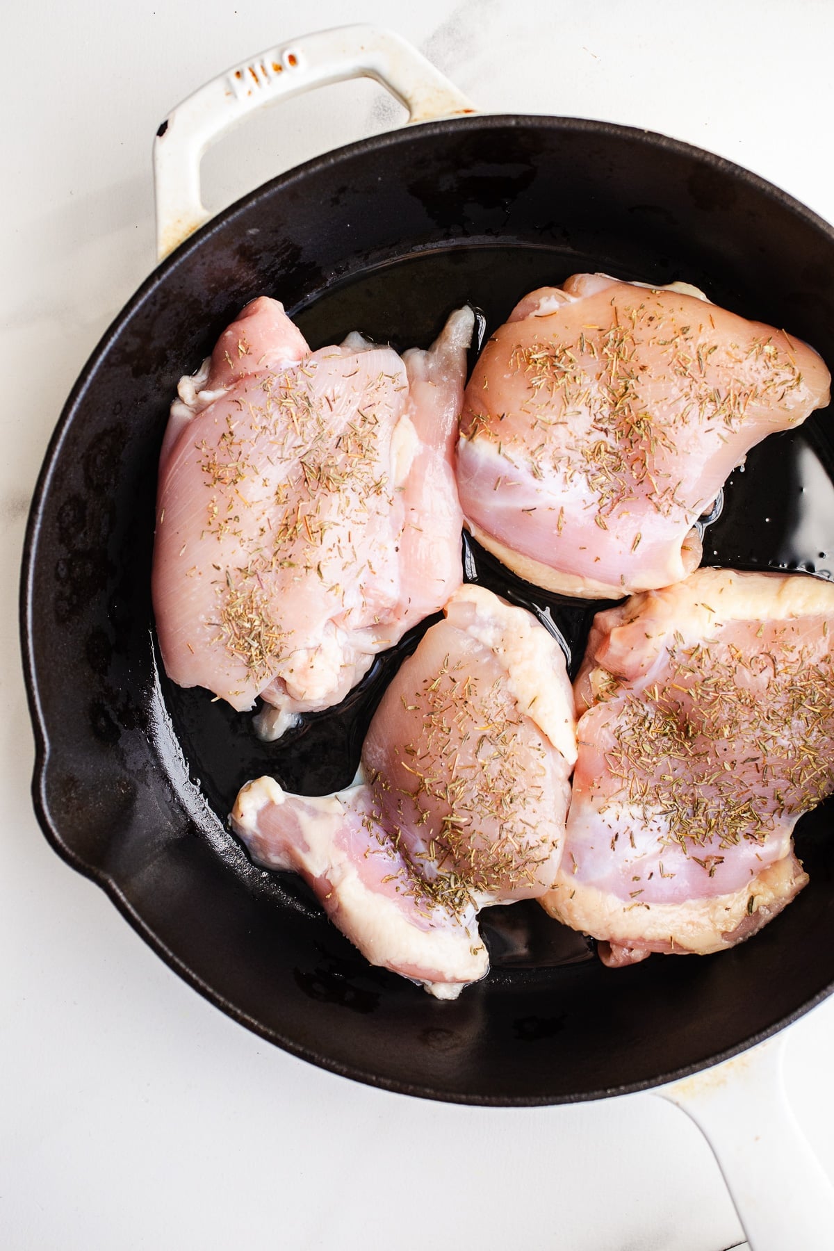Raw chicken in a skillet.