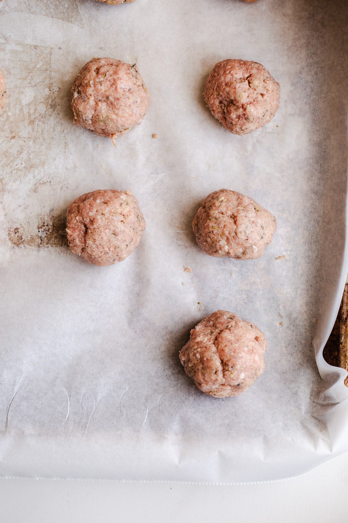 Raw meatballs on a baking sheet.