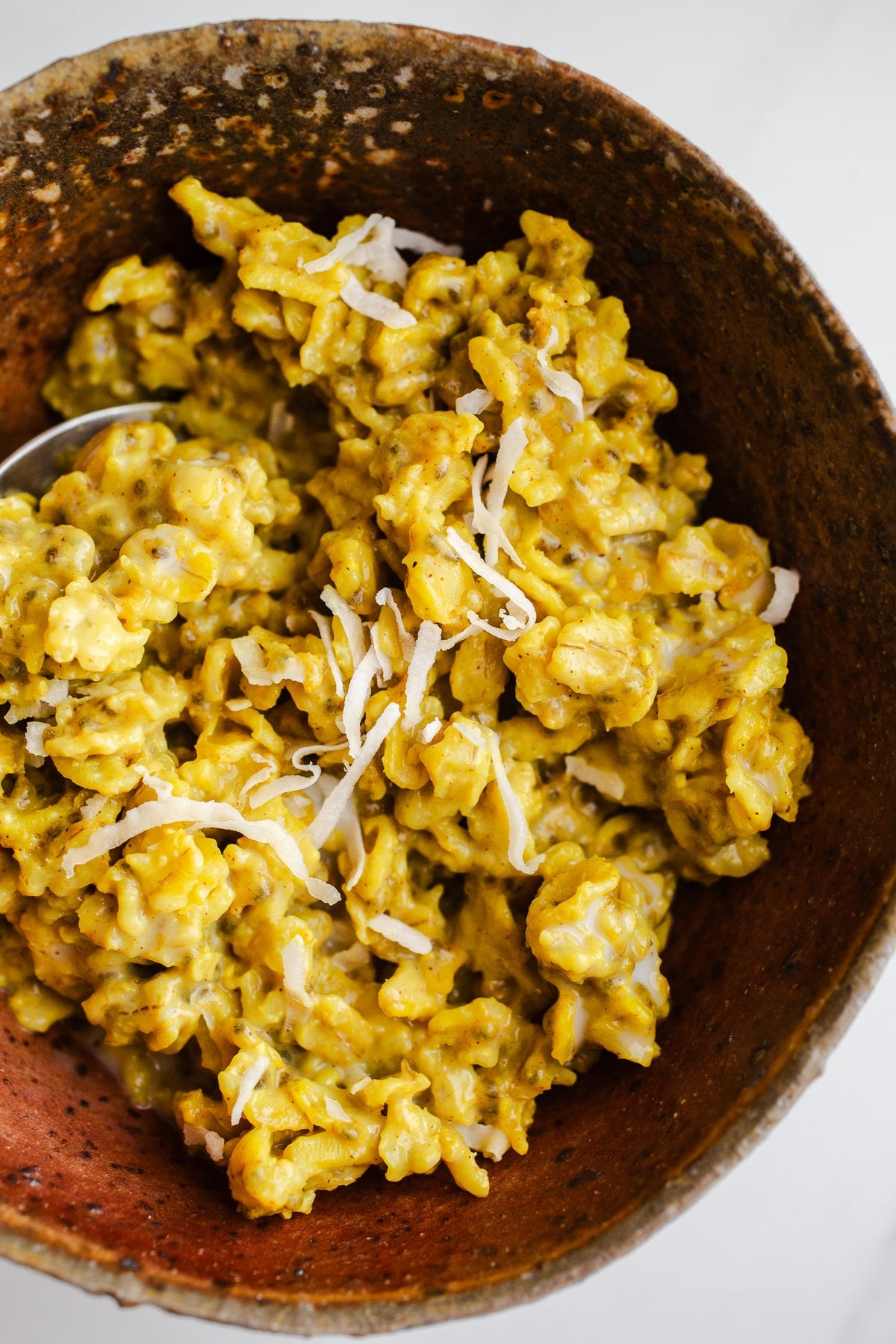 Golden colored oatmeal with coconut flakes in a bowl.