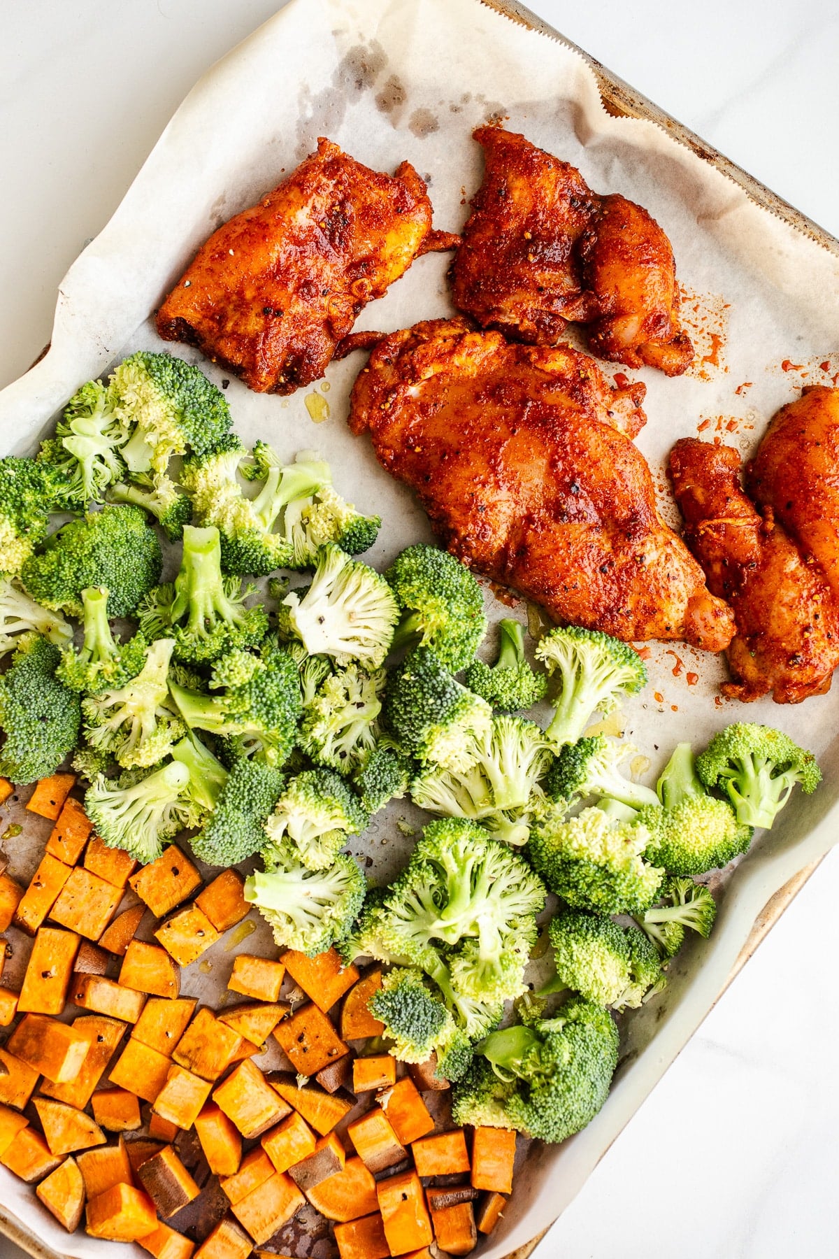 Raw chicken and veggies on a sheet pan.
