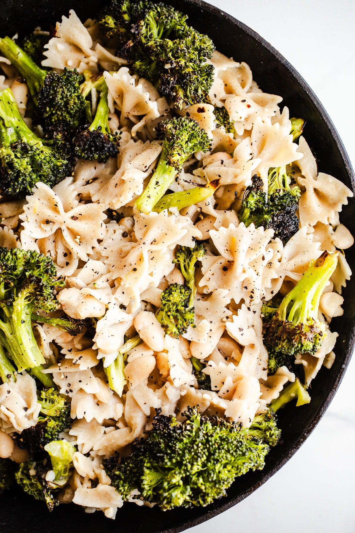 Roasted broccoli, pasta, and beans in a skillet.