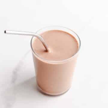 A chocolate smoothie with a metal straw.