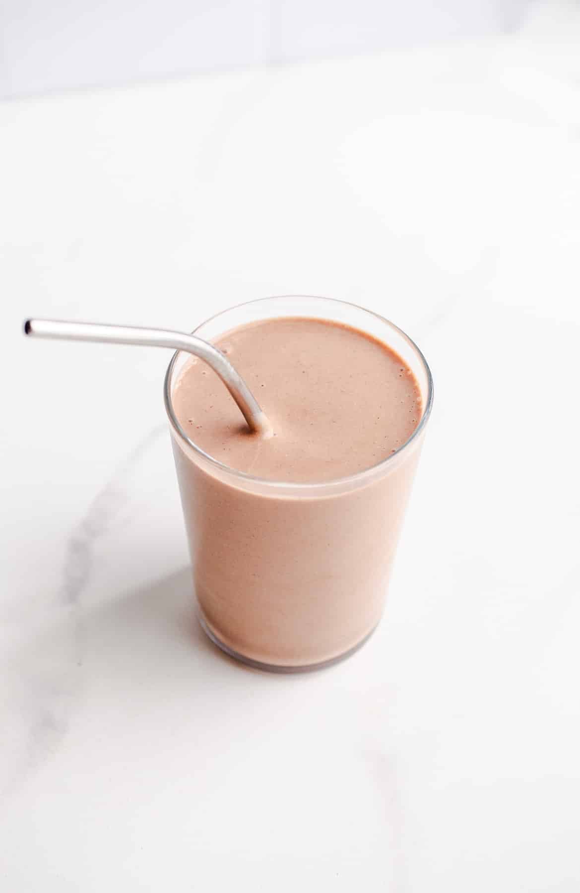 A chocolate smoothie with a metal straw.