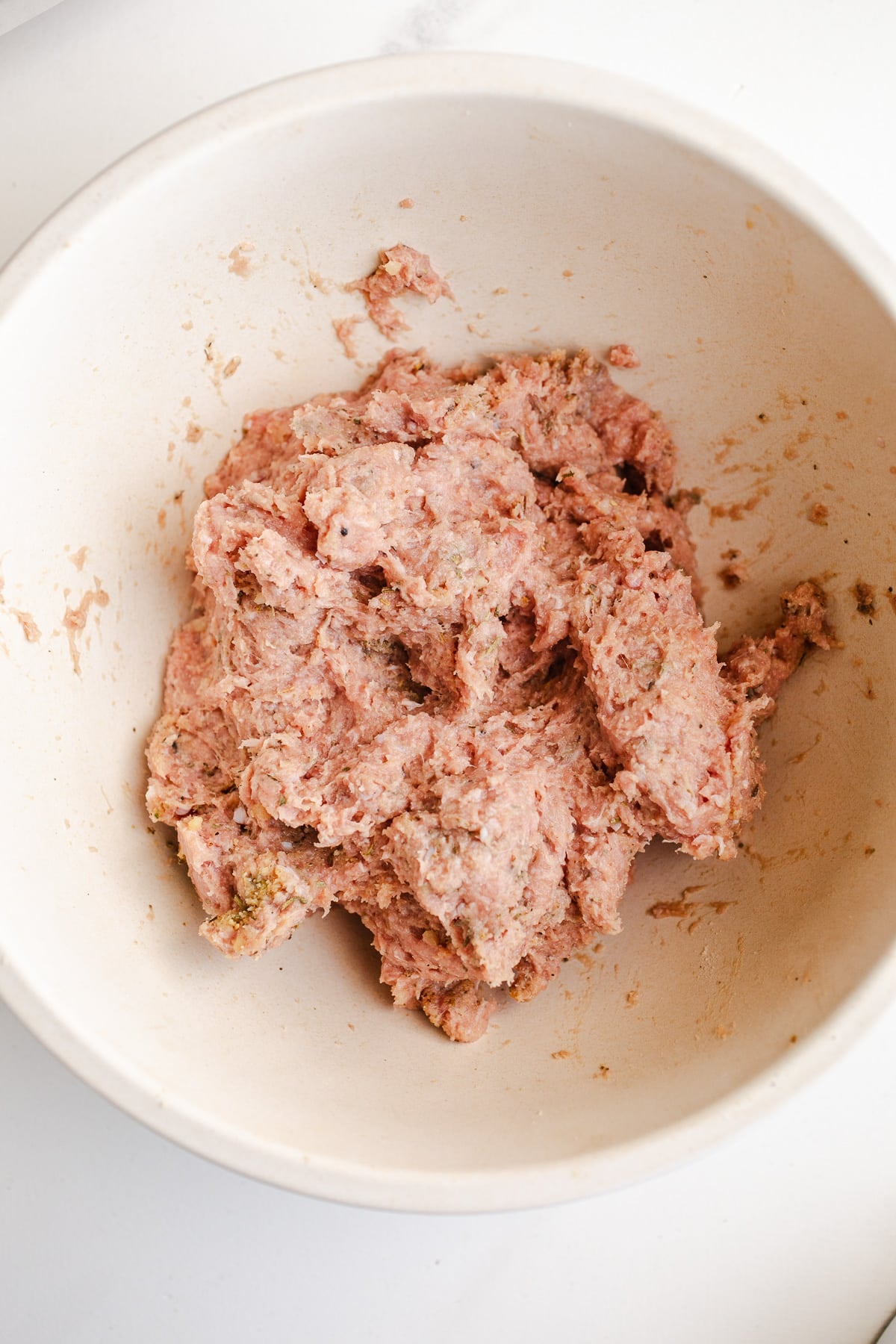 Turkey mixed with seasoning in a bowl.