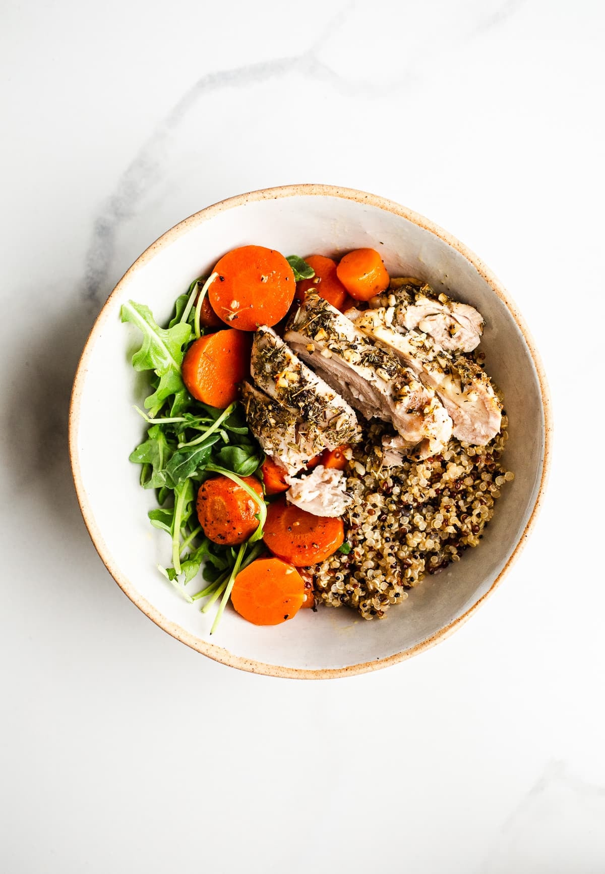 Quinoa, carrots, and baked chicken in a bowl. 