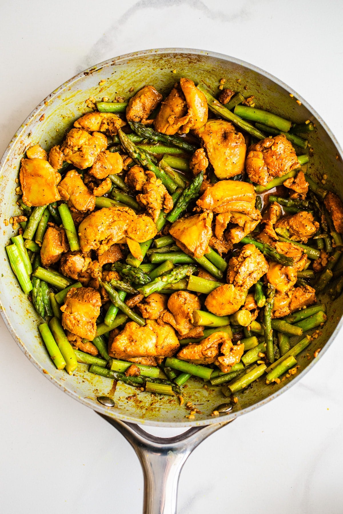 Chicken and asparagus in a pan.