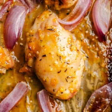 Chicken and red onions on a sheet pan.