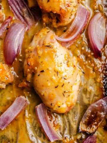 Chicken and red onions on a sheet pan.