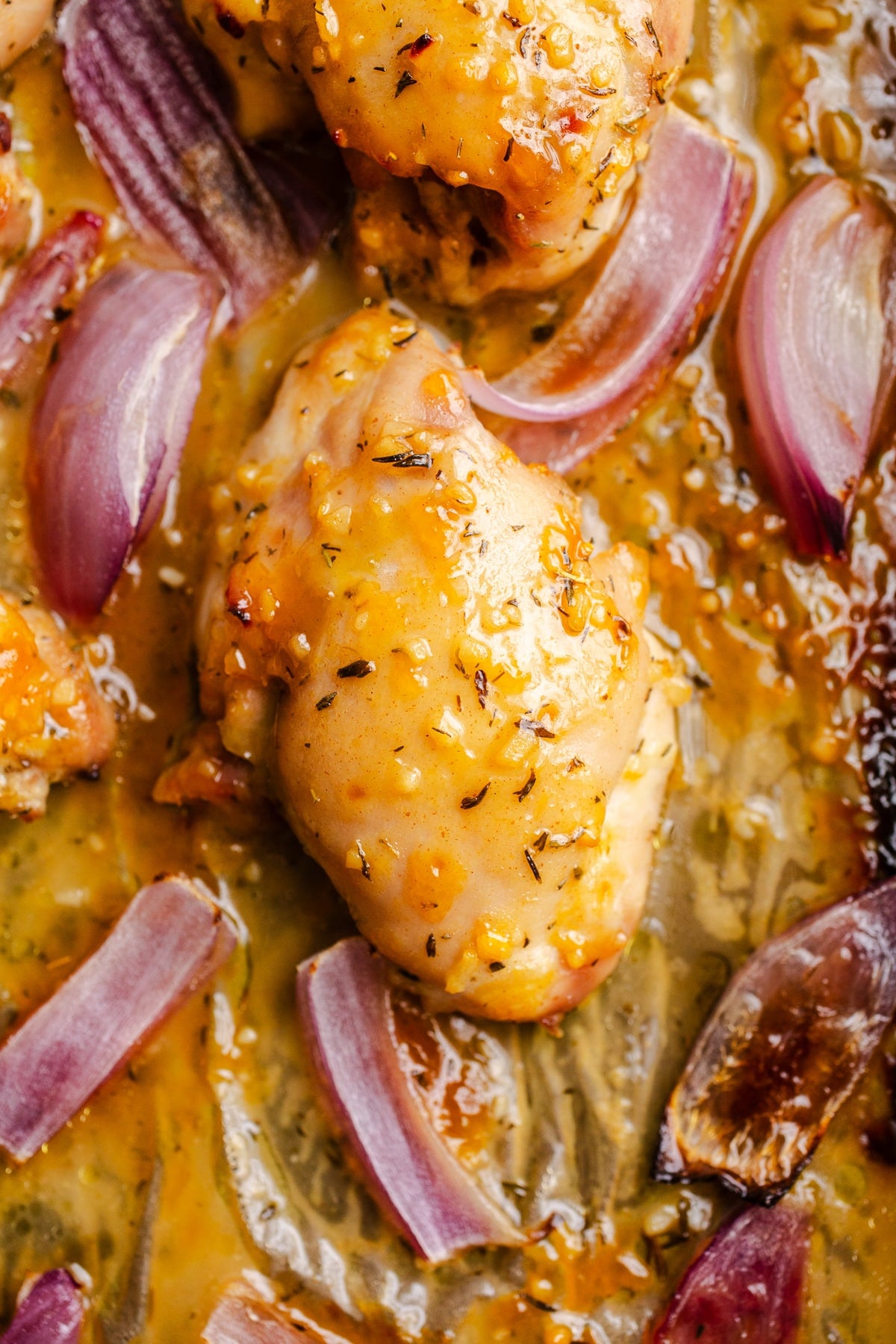 Chicken and red onions on a sheet pan.