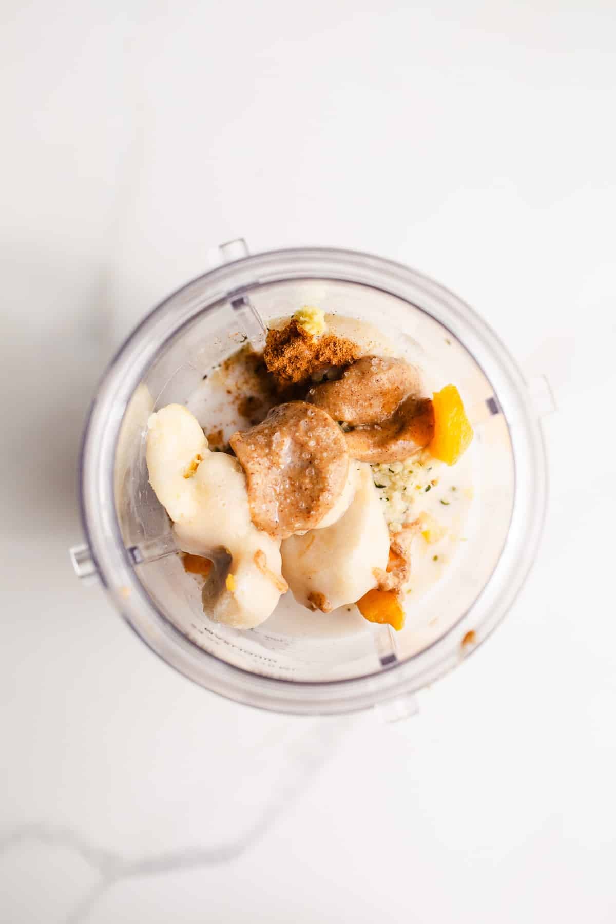 Peaches, bananas, and spices in a blender cup.
