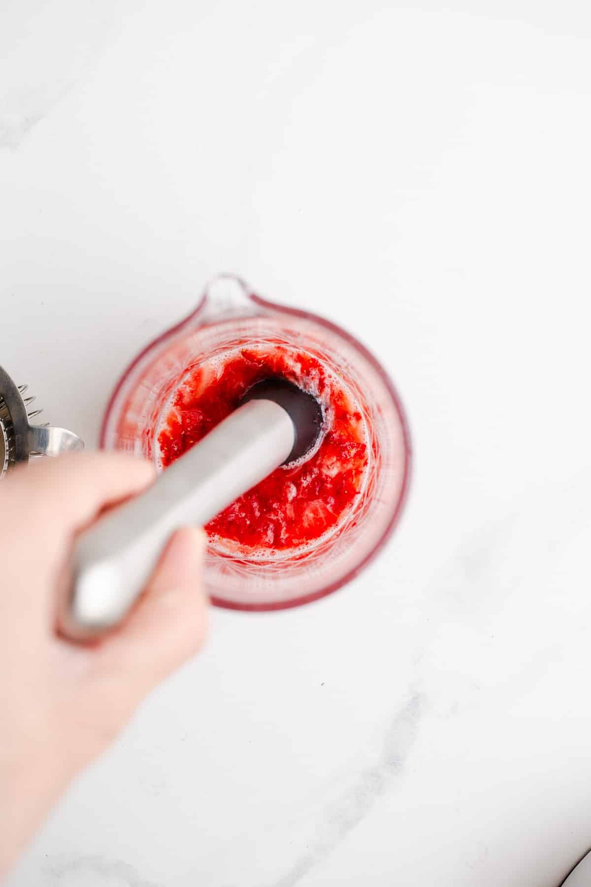 Macerating strawberries in a cocktail glass.
