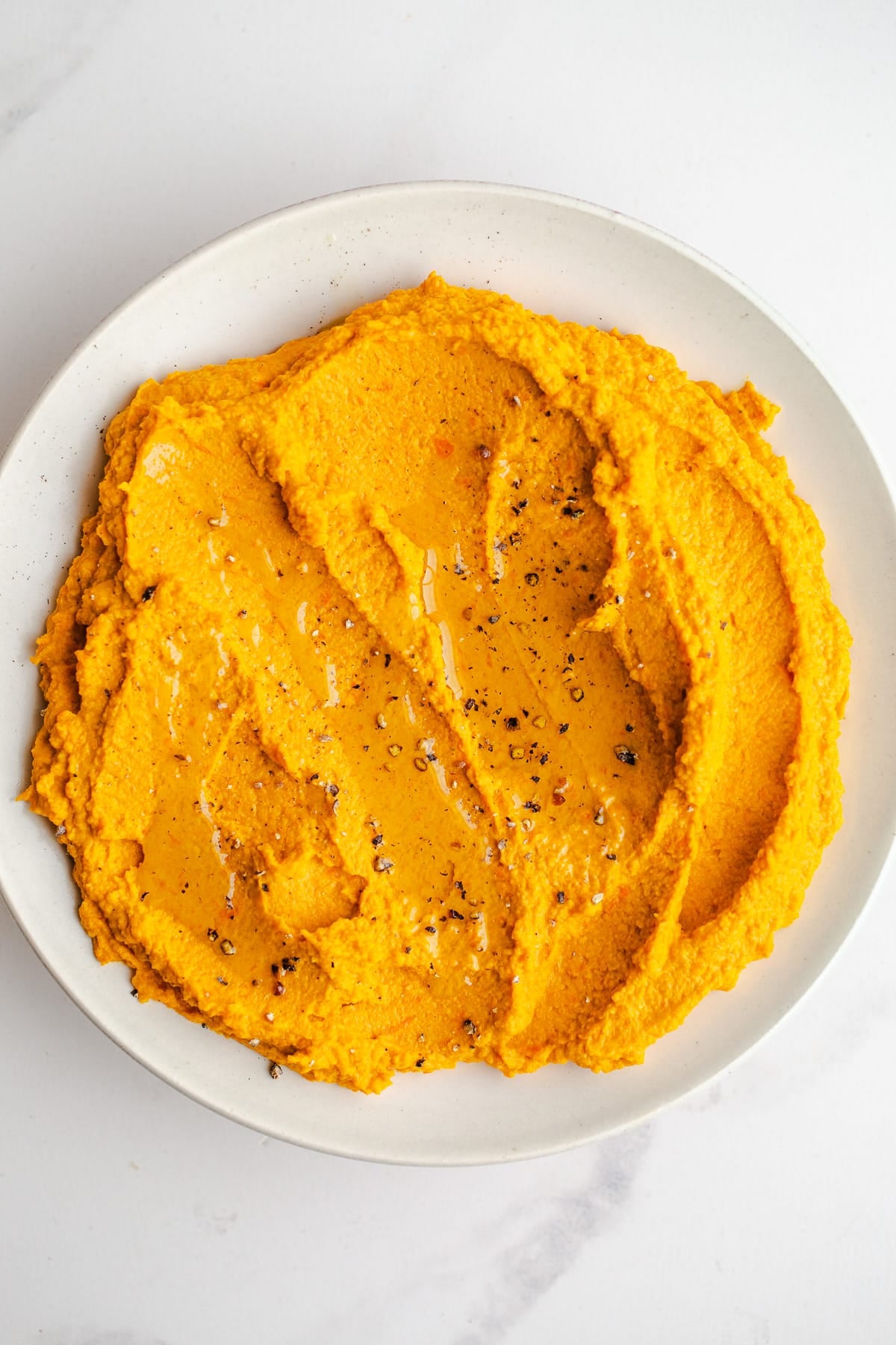 Roasted carrot turmeric hummus in a serving bowl.