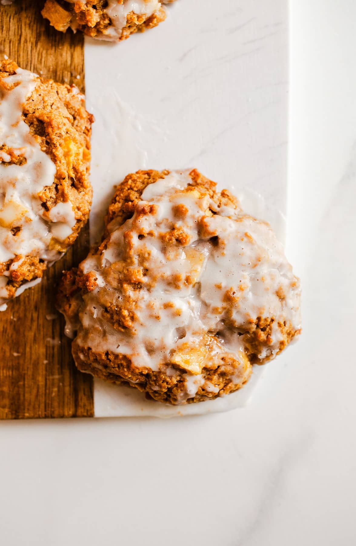 Glazed apple fritters on a serving board.