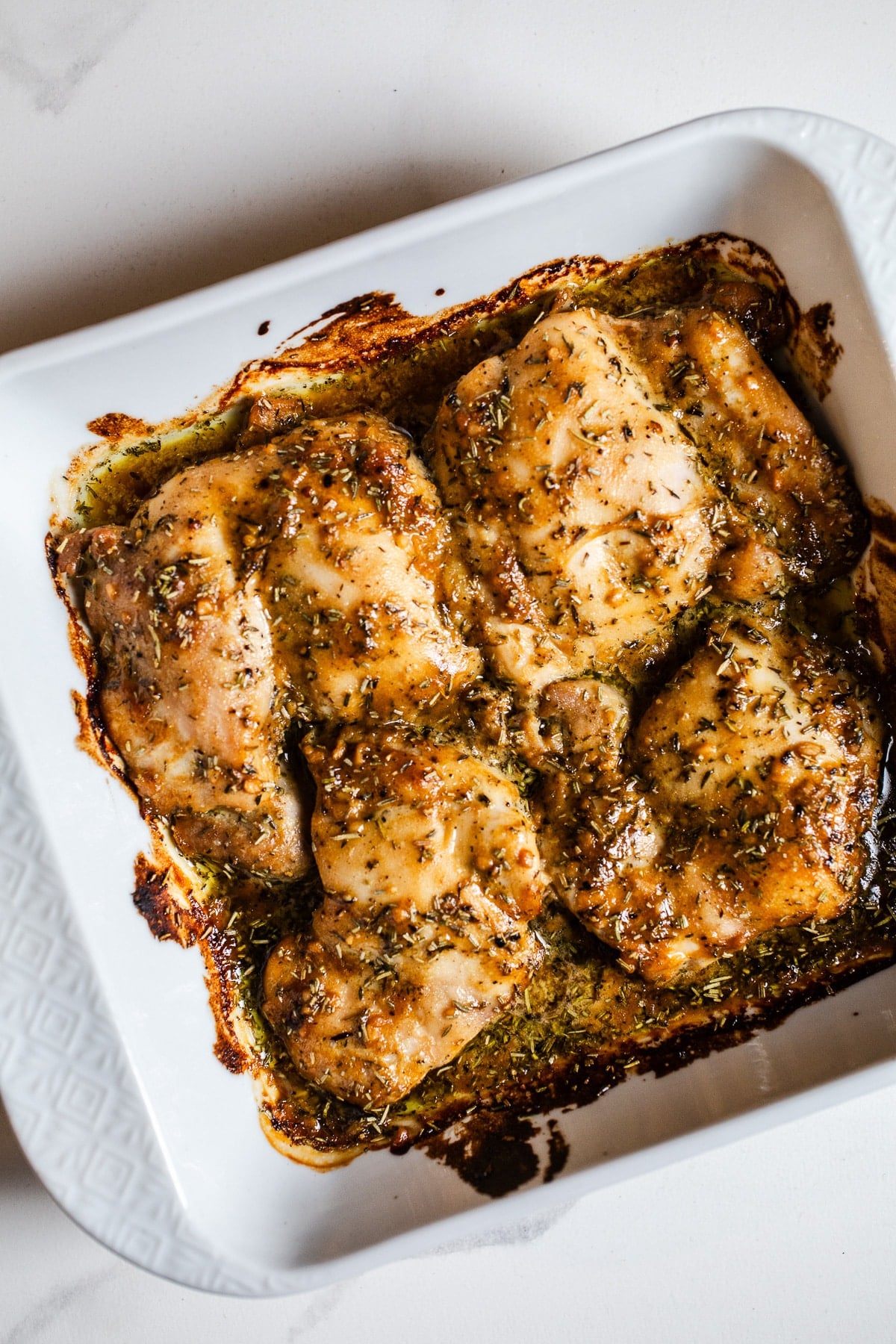 Baked maple dijon chicken in a white dish.